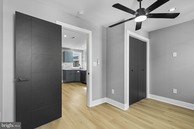 bedroom with sink, light hardwood / wood-style floors, a closet, and ceiling fan