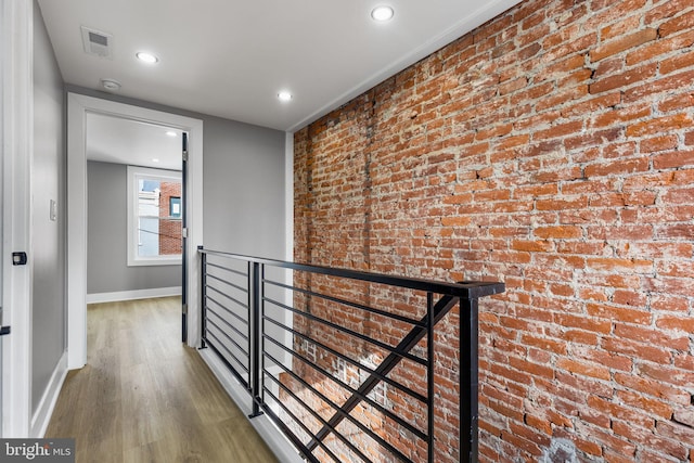 hallway featuring brick wall and hardwood / wood-style floors