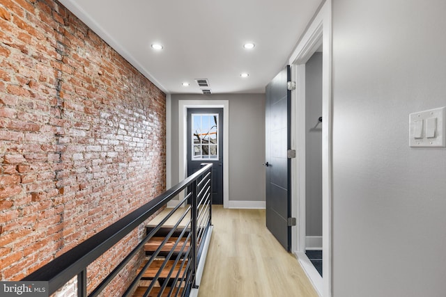 corridor featuring brick wall and light wood-type flooring