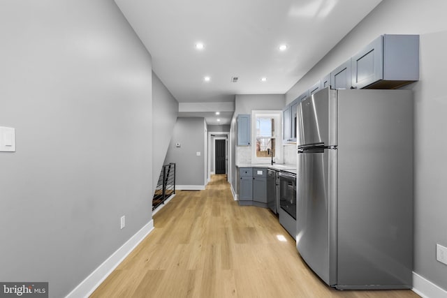 kitchen featuring electric stove, dishwashing machine, stainless steel fridge, backsplash, and light hardwood / wood-style floors