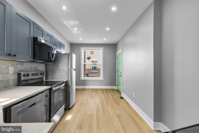 kitchen featuring tasteful backsplash, appliances with stainless steel finishes, blue cabinets, and light hardwood / wood-style floors