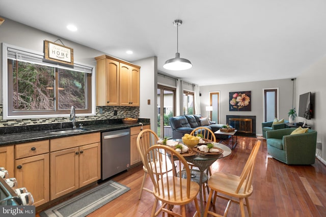 kitchen featuring tasteful backsplash, dishwasher, sink, hanging light fixtures, and light brown cabinets