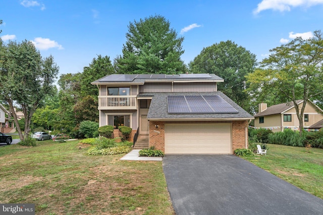 view of front of property featuring a garage, a balcony, a front yard, and solar panels