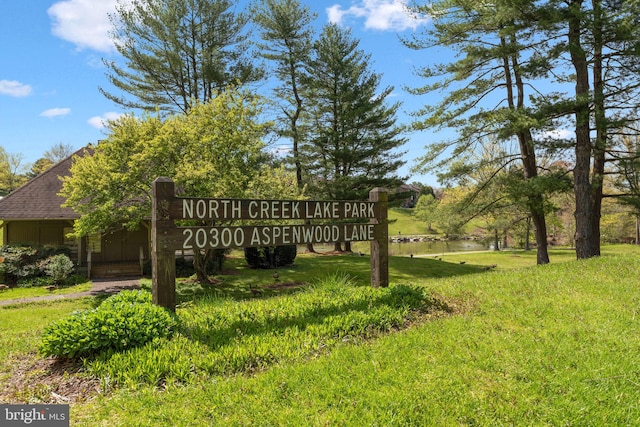 community / neighborhood sign featuring a water view and a lawn