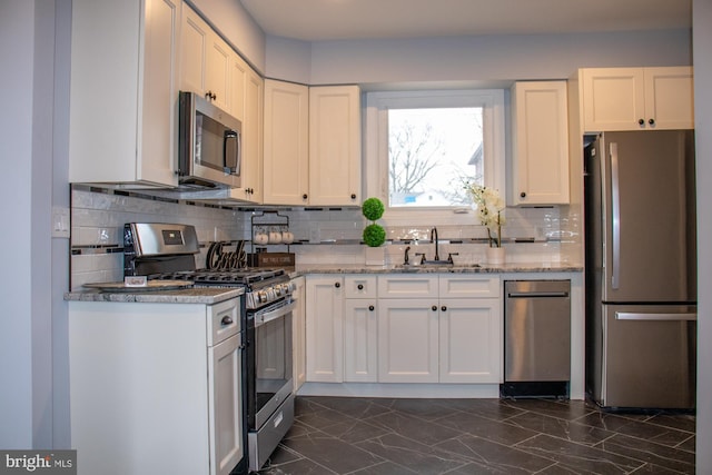 kitchen with light stone counters, stainless steel appliances, sink, and white cabinets