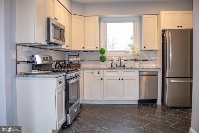 kitchen with white cabinetry, appliances with stainless steel finishes, light stone countertops, and sink