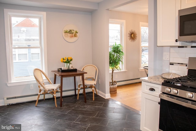 kitchen with stainless steel appliances, white cabinetry, tasteful backsplash, and baseboard heating