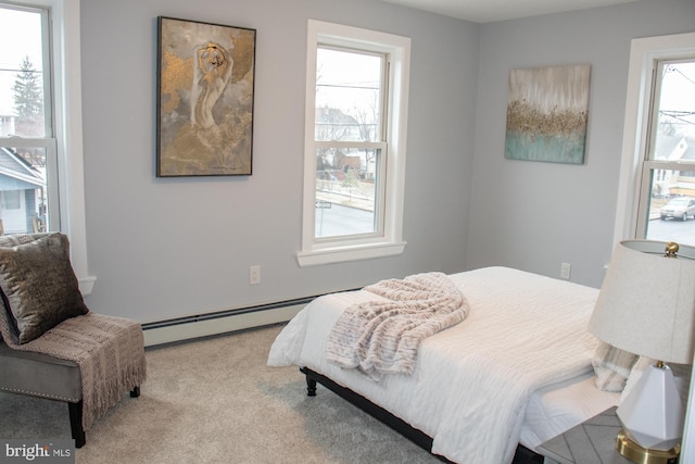 bedroom featuring a baseboard heating unit and light colored carpet