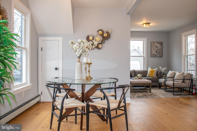 dining space featuring baseboard heating, wood-type flooring, and plenty of natural light