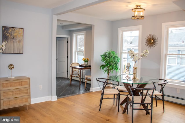 dining space with a baseboard heating unit and wood-type flooring