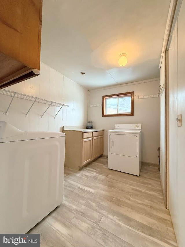 laundry area with cabinets, washing machine and dryer, sink, and light wood-type flooring