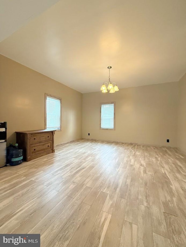 unfurnished living room featuring an inviting chandelier and light hardwood / wood-style floors