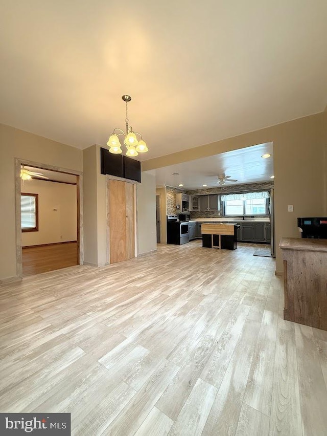 unfurnished living room featuring a chandelier and light hardwood / wood-style flooring