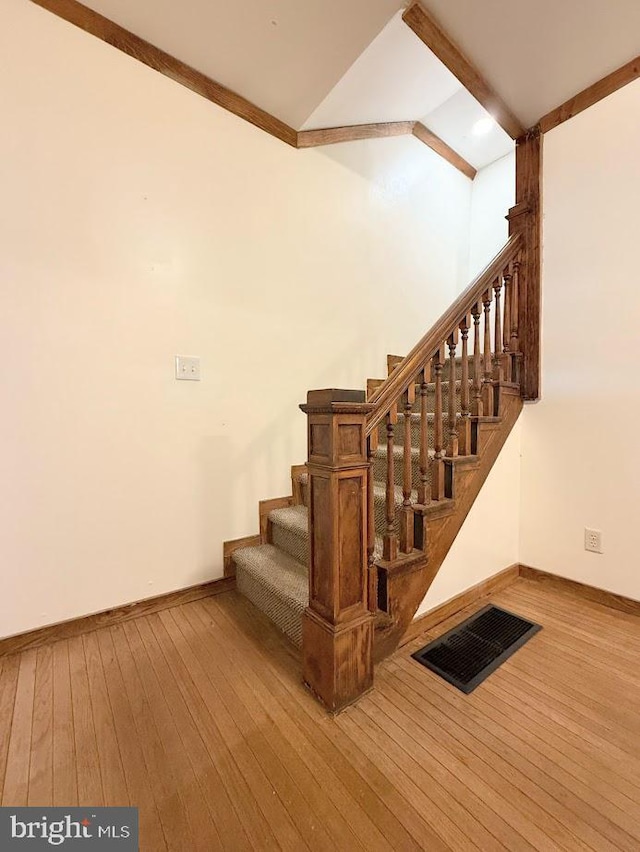 stairs featuring wood-type flooring and vaulted ceiling