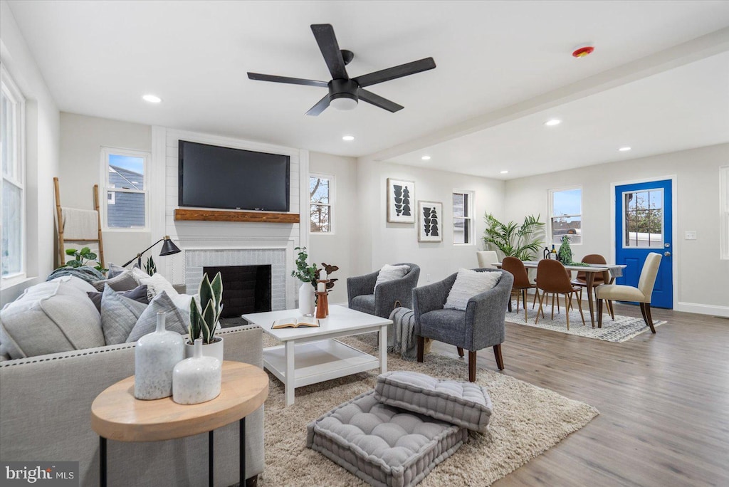 living room with a fireplace, wood-type flooring, and ceiling fan