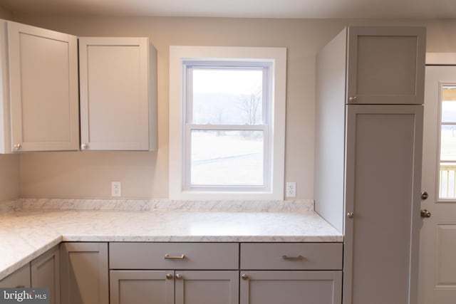 kitchen featuring gray cabinetry, light stone counters, and plenty of natural light