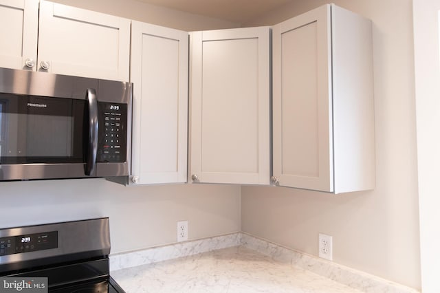 kitchen with light stone countertops, white cabinets, and stove