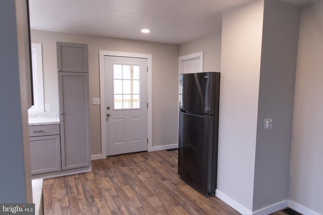 kitchen with black refrigerator, gray cabinetry, and dark hardwood / wood-style flooring