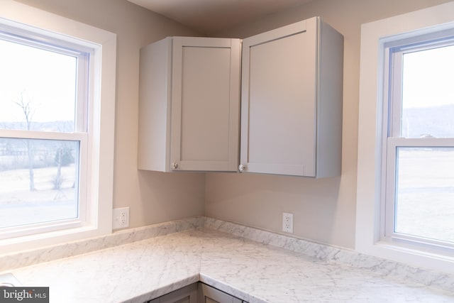 kitchen with gray cabinetry and light stone counters