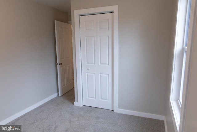 unfurnished bedroom featuring light colored carpet and a closet