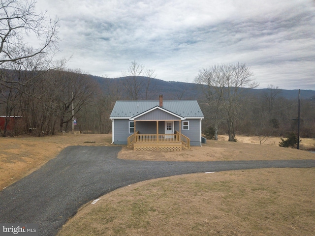 view of front of house with a porch, a mountain view, and a front lawn