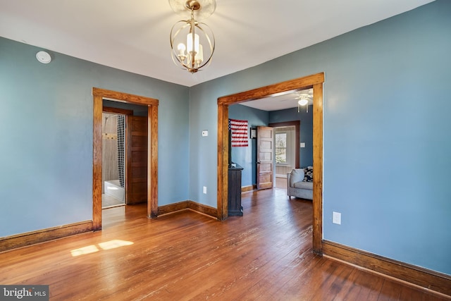 unfurnished room featuring hardwood / wood-style flooring, baseboards, and a chandelier