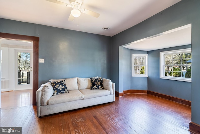 living area with a ceiling fan, hardwood / wood-style flooring, visible vents, and baseboards