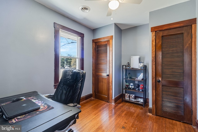 office featuring hardwood / wood-style floors, baseboards, visible vents, and ceiling fan