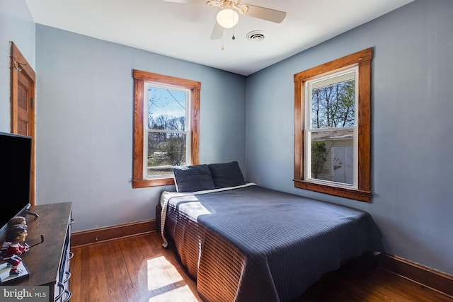 bedroom featuring visible vents, wood-type flooring, baseboards, and a ceiling fan