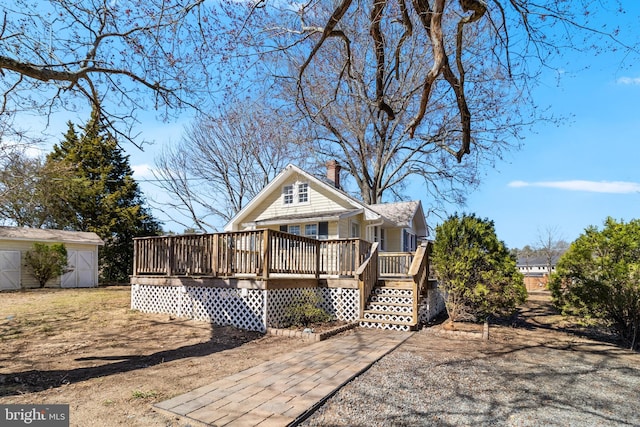 rear view of house featuring a storage unit, a wooden deck, an outbuilding, and a chimney