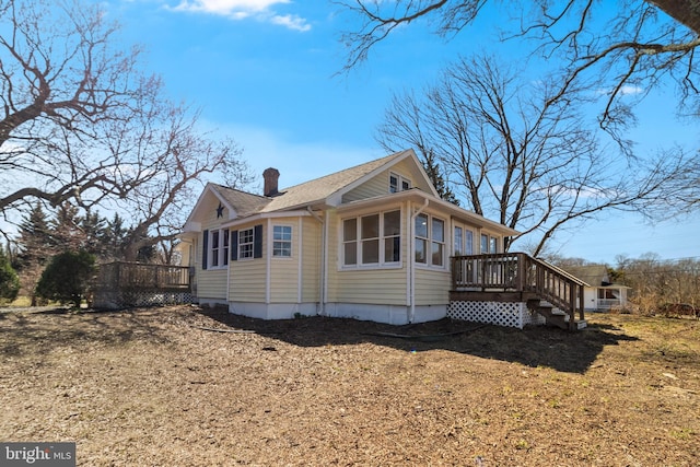 view of side of property featuring a chimney and a wooden deck