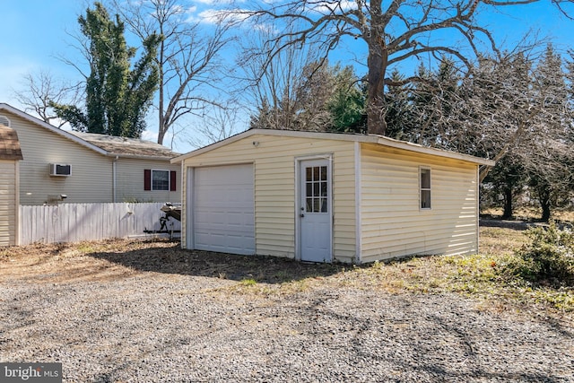 detached garage featuring driveway and fence