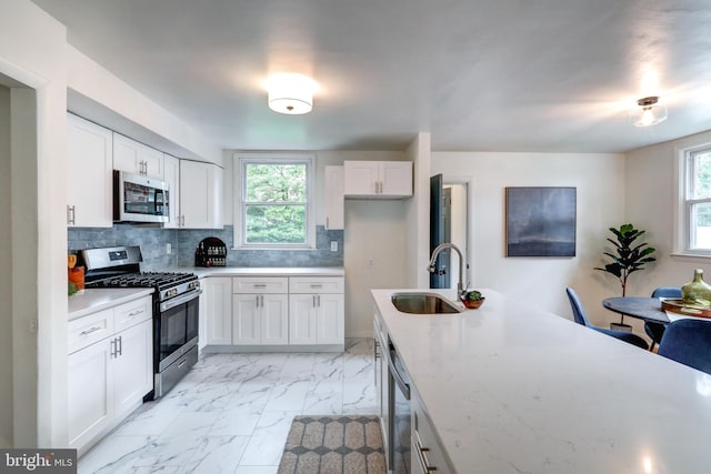 kitchen featuring a healthy amount of sunlight, stainless steel appliances, sink, and white cabinets