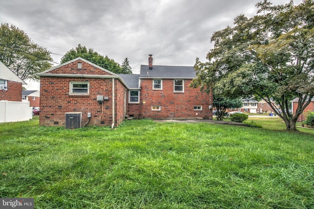 rear view of house featuring central AC and a lawn