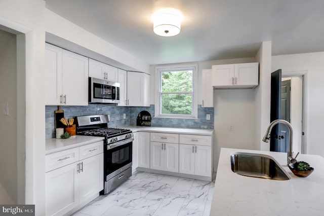 kitchen featuring stainless steel appliances, sink, decorative backsplash, and white cabinets