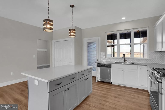 kitchen with appliances with stainless steel finishes, decorative light fixtures, sink, backsplash, and a center island