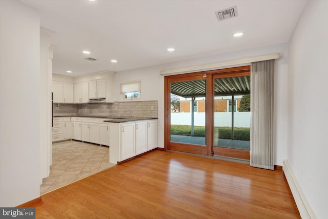 kitchen with white cabinetry, light wood-type flooring, decorative backsplash, and a baseboard heating unit