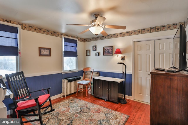 sitting room featuring radiator, hardwood / wood-style floors, and ceiling fan