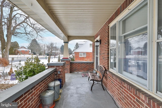 snow covered patio featuring covered porch