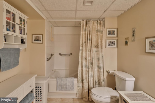 bathroom with toilet, tile patterned flooring, a drop ceiling, and shower / bath combo