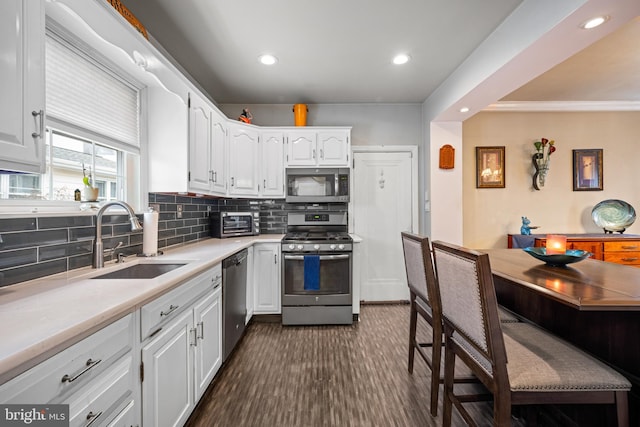 kitchen with sink, dark wood-type flooring, stainless steel appliances, white cabinets, and decorative backsplash