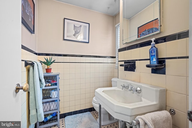 bathroom with toilet, tile patterned flooring, and tile walls