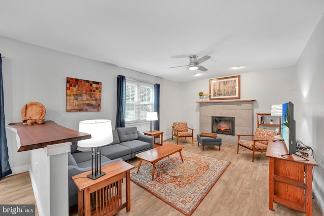 living room with light wood-type flooring, a tile fireplace, and baseboards