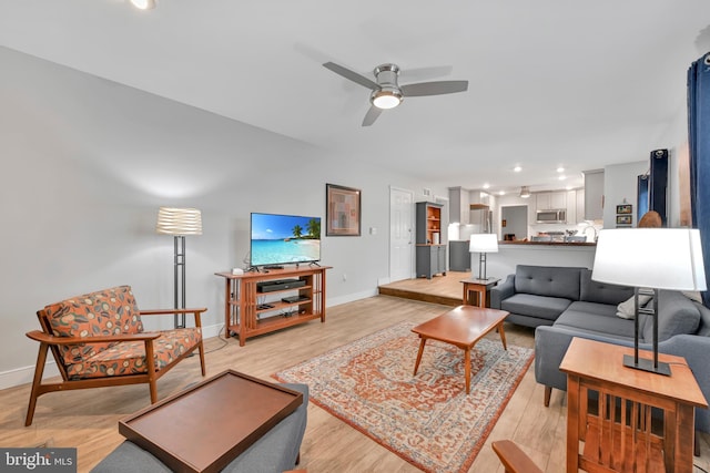 living room featuring a ceiling fan, recessed lighting, baseboards, and light wood finished floors