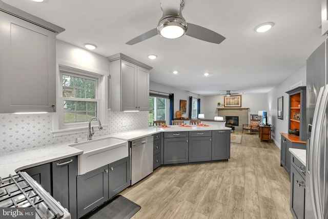 kitchen featuring stainless steel appliances, gray cabinets, a peninsula, and a sink