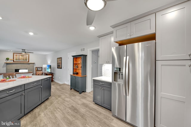 kitchen with ceiling fan, stainless steel refrigerator with ice dispenser, gray cabinets, and visible vents