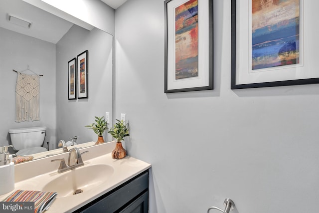 half bath with toilet, visible vents, and vanity