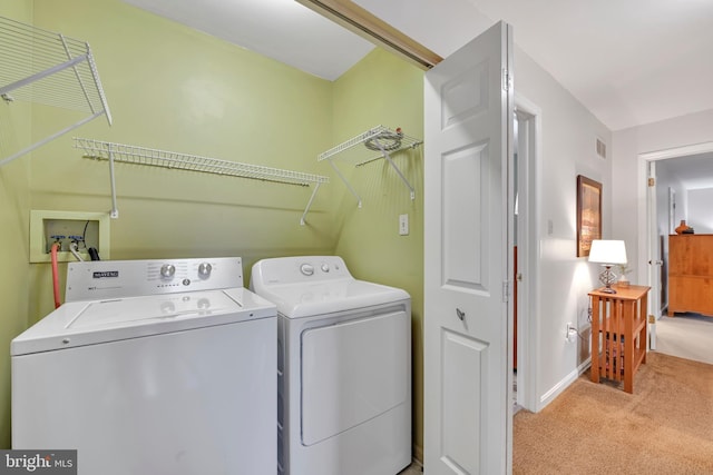 clothes washing area featuring washing machine and clothes dryer, visible vents, light carpet, laundry area, and baseboards