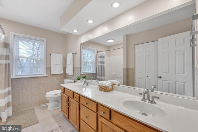 full bathroom with tile walls, a sink, toilet, and tile patterned floors