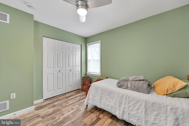 bedroom with a closet, visible vents, baseboards, and wood finished floors